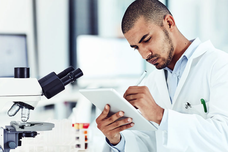 Male scientist reviewing clinical trial on tablet